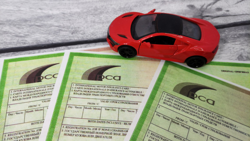 Бланки «Зелёной карты» и игрушечный автомобиль красного цвета