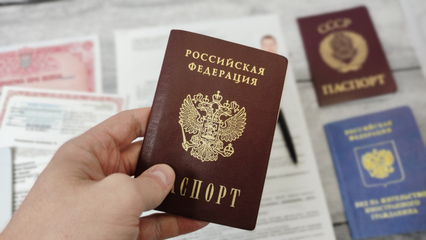 Паспорт гражданина Российской Федерации в руке на фоне документов