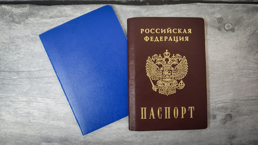 Паспорт Российской Федерации и синий документ на деревянной поверхности