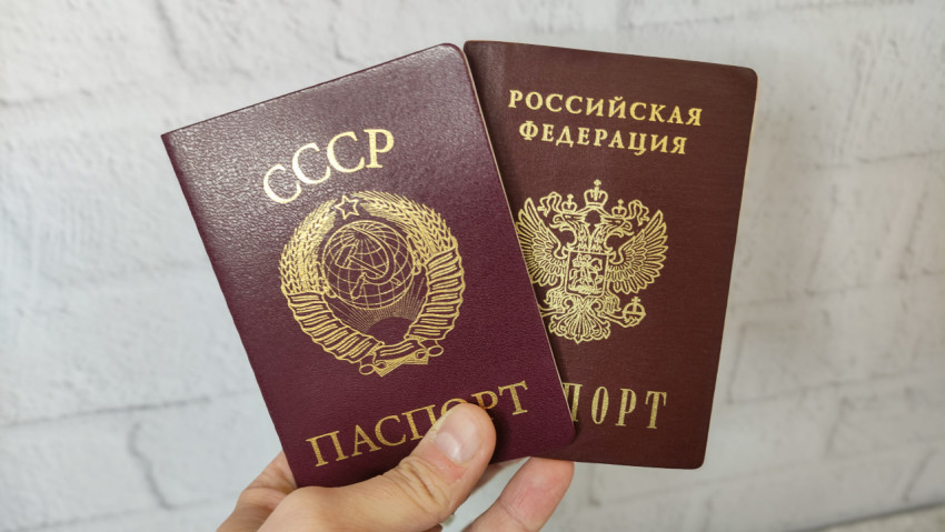 Паспорта СССР и Российской Федерации в руке на светлом фоне