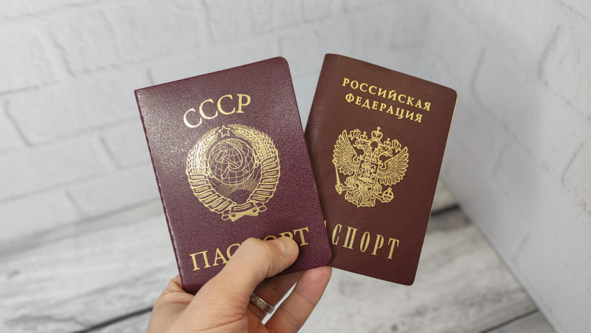 Паспорт СССР и паспорт РФ в руке на сером фоне