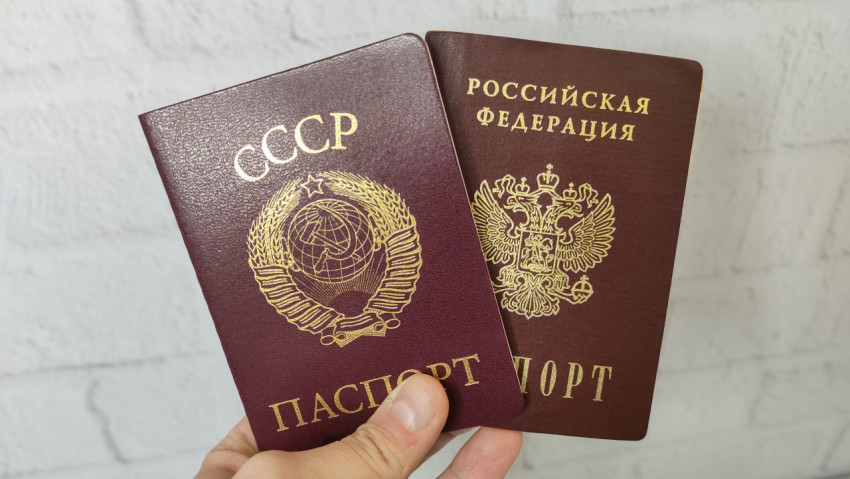 Паспорт СССР и паспорт Российской Федерации в руке на светлом фоне