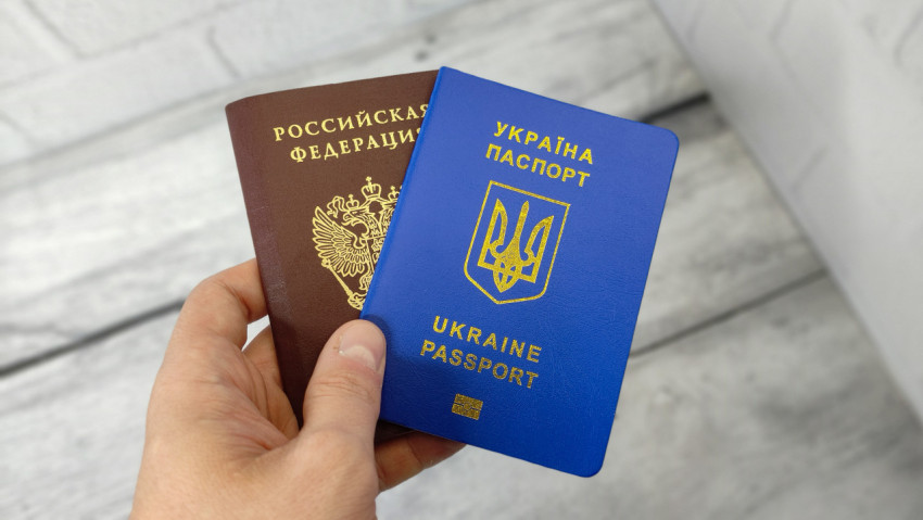 Паспорт РФ и паспорт Украины в руке на фоне светлого пола