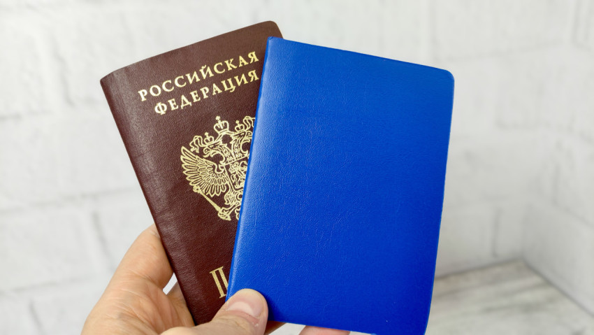 Паспорт РФ и синий документ в руке на светлом фоне