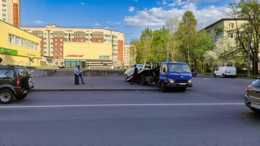 Эвакуатор загружает автомобиль во дворе жилого квартала