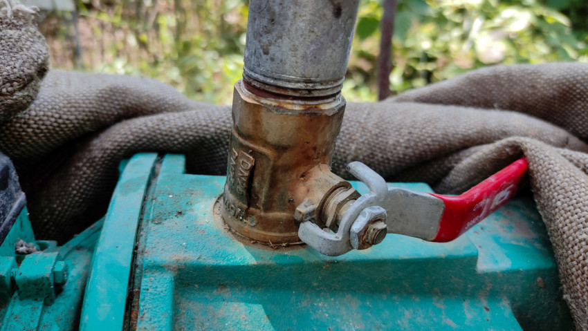 Латунный шаровой кран с красной ручкой на металлической трубе