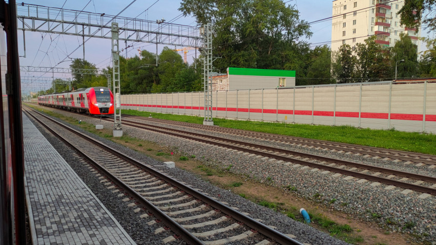 Пригородный поезд на железнодорожных путях у шумозащитного экрана