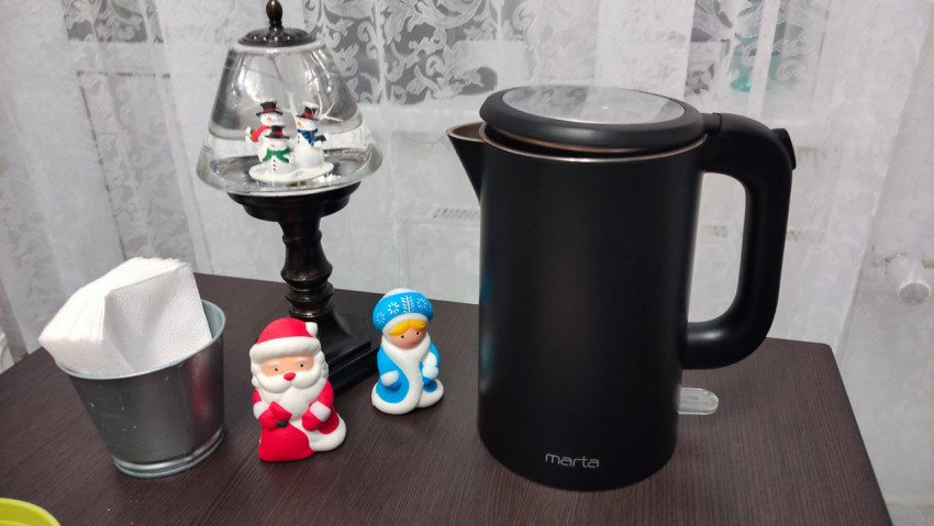 Электрический чайник на столе с новогодними фигурками