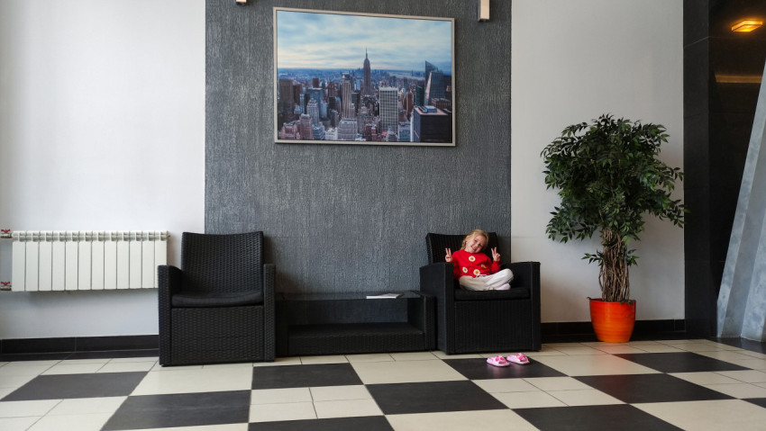 Девочка сидит в кресле под постером панорамы Нью-Йорка