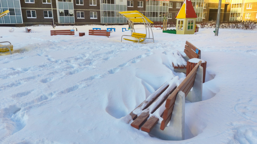 Заснеженная детская площадка во дворе жилого комплекса