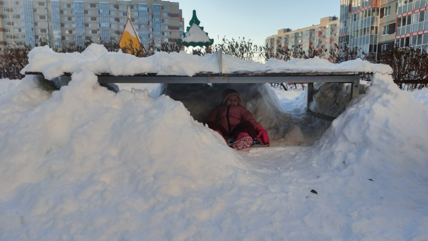 Ребёнок играет в снежной пещере на детской площадке