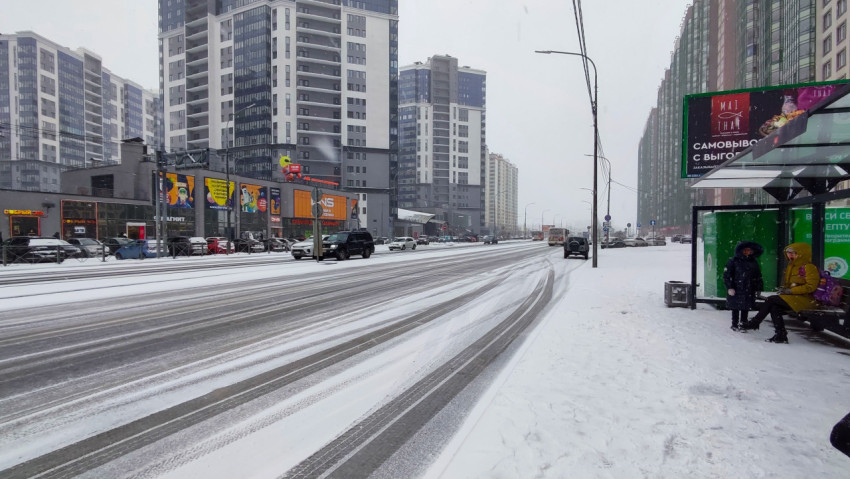 Заснеженная городская магистраль и современная жилая застройка