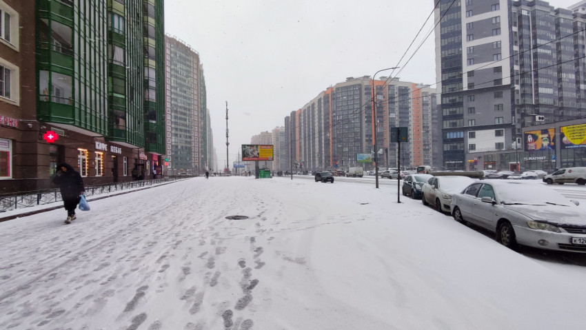 Пешеходы и автомобили на заснеженной улице современного жилого района