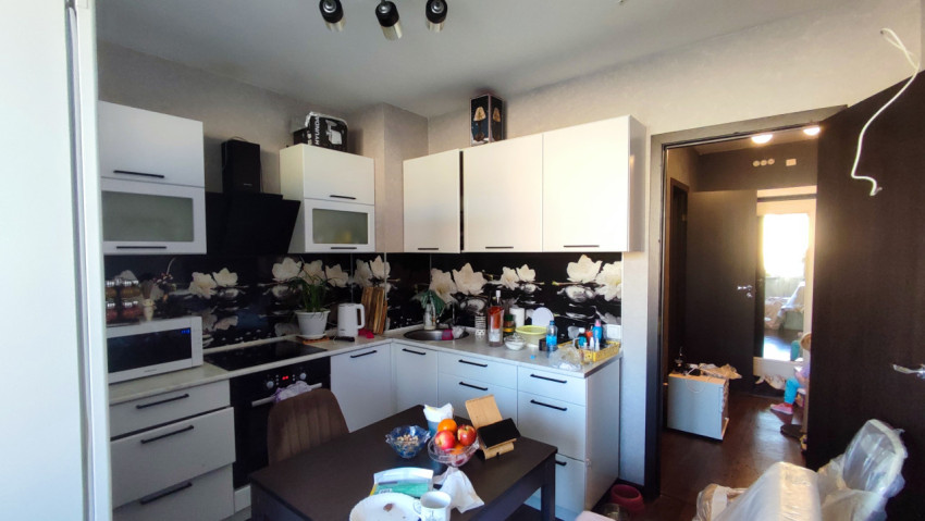 Вид кухни в жилой квартире с мебелью и бытовой техникой