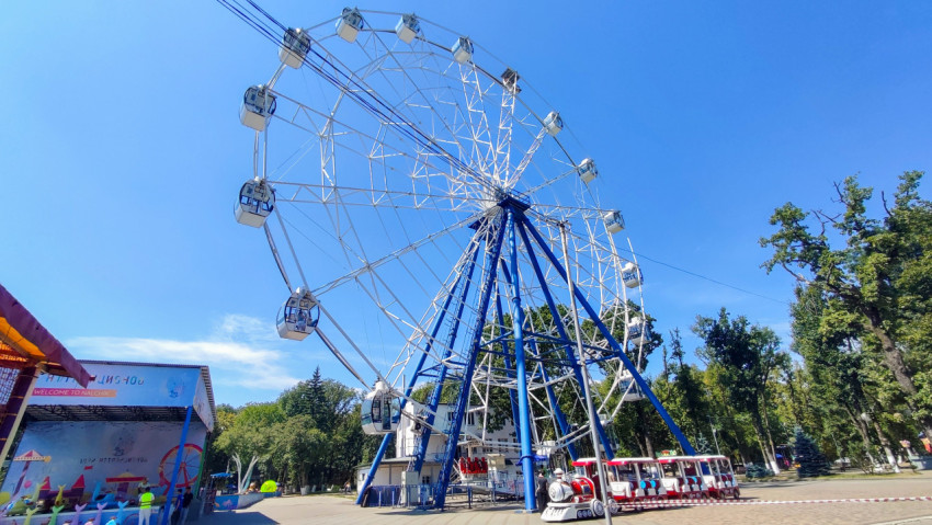 Колесо обозрения на аллее парка в солнечный день