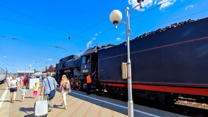 Паровоз с тендером на платформе станции под контактной сетью и фонарями