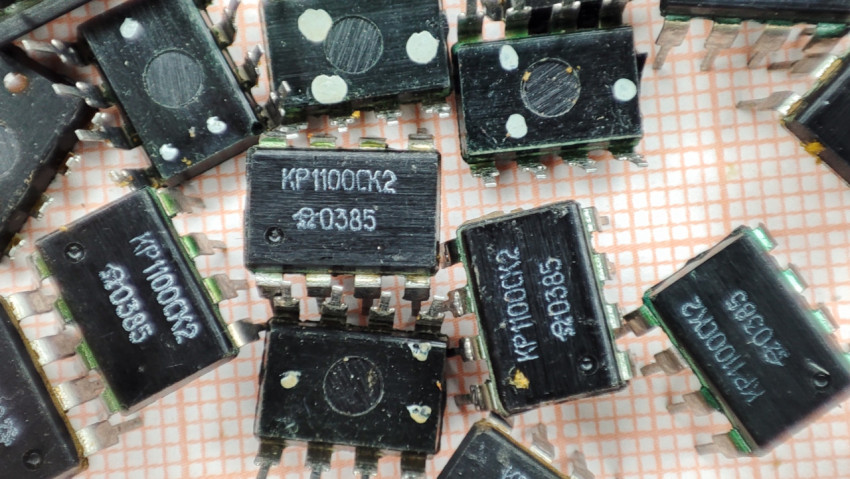 Микросхемы КР1100СК2 россыпью на фоне миллиметровки