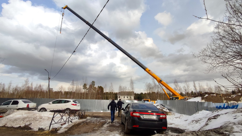 Кран с длинной стрелой за ограждением на строительной площадке