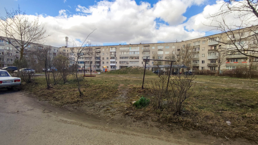 Двор многоквартирного дома с качелями и зелеными насаждениями