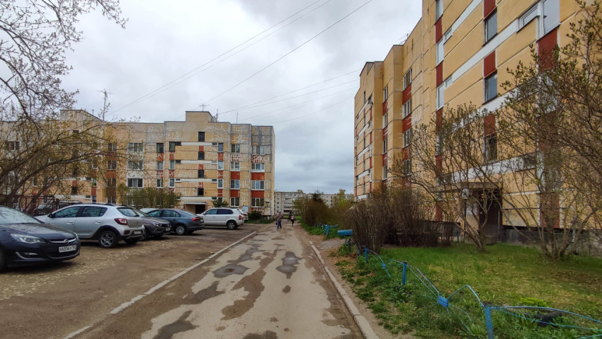 Двор жилых домов с парковкой и зелеными насаждениями в облачный день