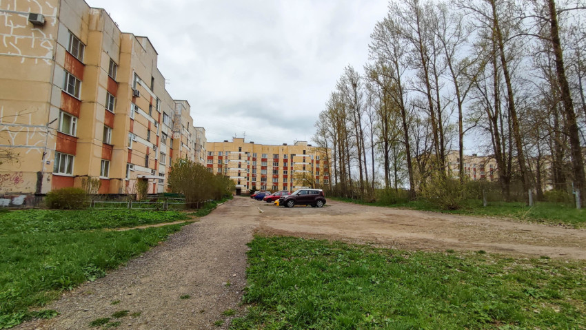Двор многоквартирного дома с парковкой и зелеными деревьями