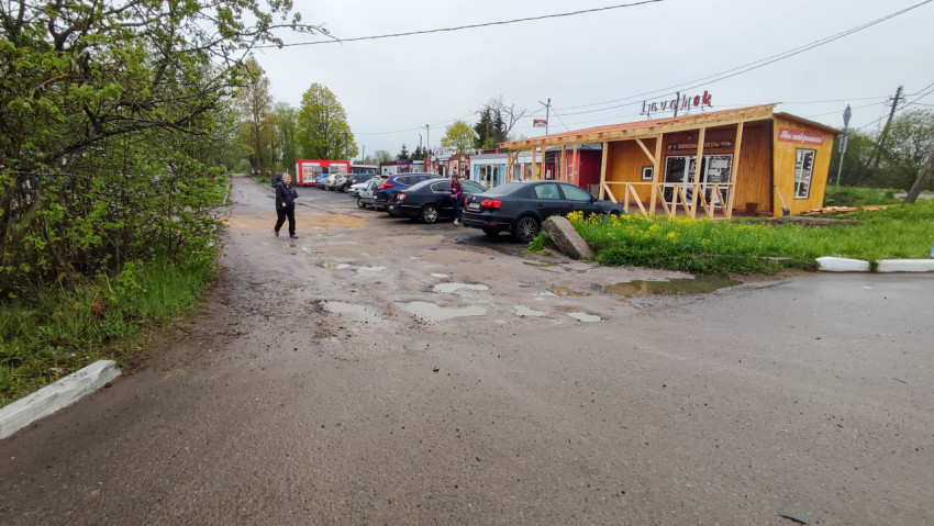 Разбитая дорога и магазины на окраине города в дождливую погоду
