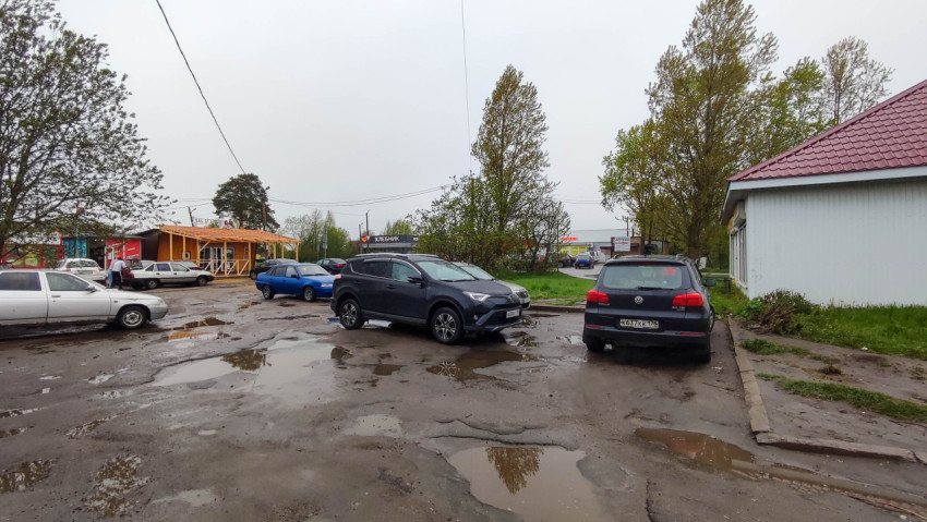 Пейзаж с припаркованными автомобилями и лужами в плохую погоду