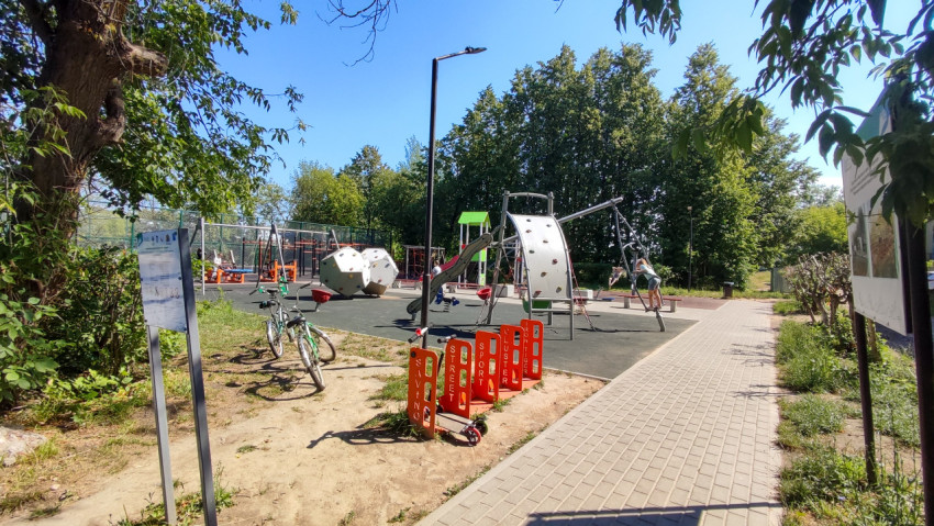 Яркая детская площадка с игровыми комплексами в окружении деревьев