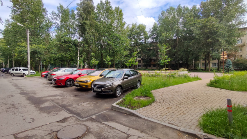 Парковка рядом с дорогой в жилом районе под облачным небом