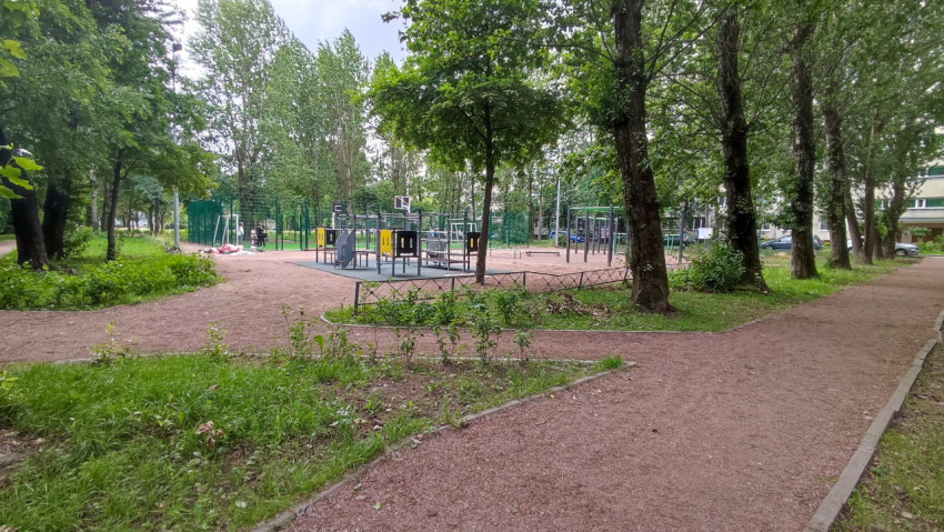 Спортивная площадка в городском сквере, окруженная зелеными деревьями