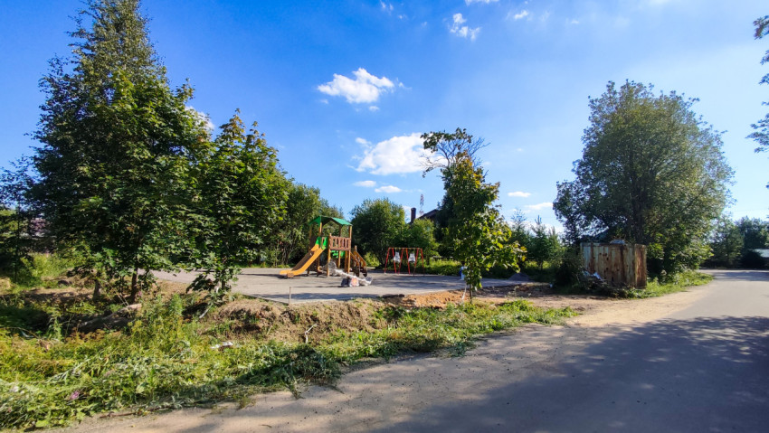 Детская площадка с горками и качелями в окружении деревьев