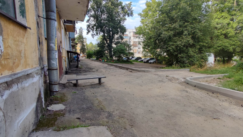 Двор жилого дома с парковкой и зелеными деревьями