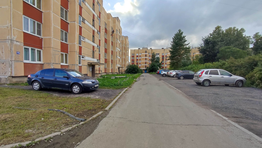 Двор многоквартирного дома с припаркованными автомобилями и зелёными насаждениями