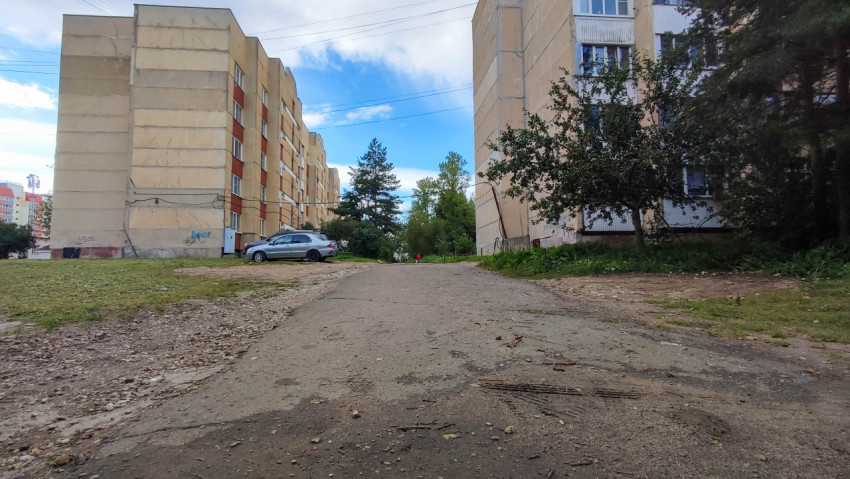 Двор многоквартирного дома с дорожным покрытием и зелеными насаждениями