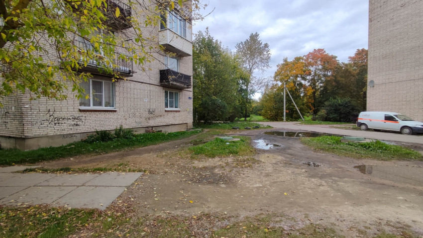 Дворовая территория с лужами возле кирпичного дома