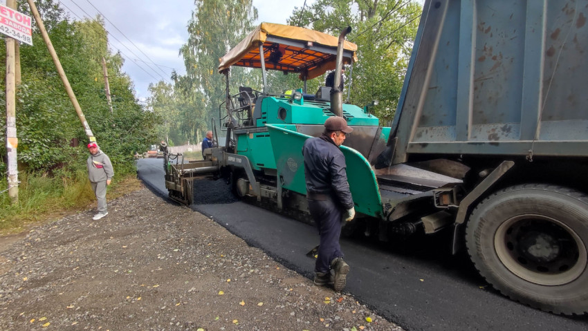 Работа асфальтоукладчика на участке дороги в лесистой местности