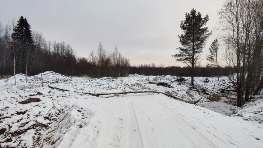 Заснеженная территория с трубами и земляными работами в лесу