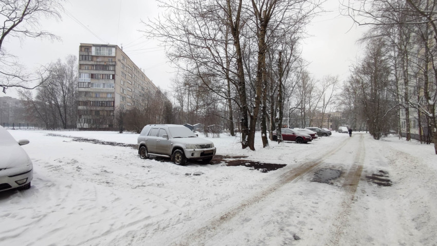 Заснеженный двор жилого района с припаркованными машинами
