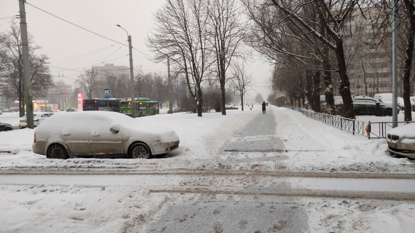 Заснеженная городская улица с припаркованными машинами