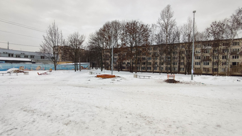 Заснеженная дворовая территория с детской площадкой и жилыми домами