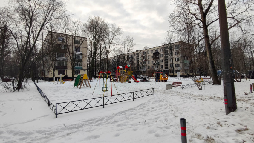 Заснеженная детская площадка во дворе многоквартирного дома