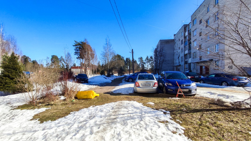 Автомобили на припаркованной площадке среди снега и кустарников