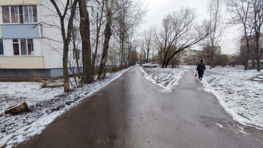 Пешеходная дорожка вдоль дома зимой после оттепели
