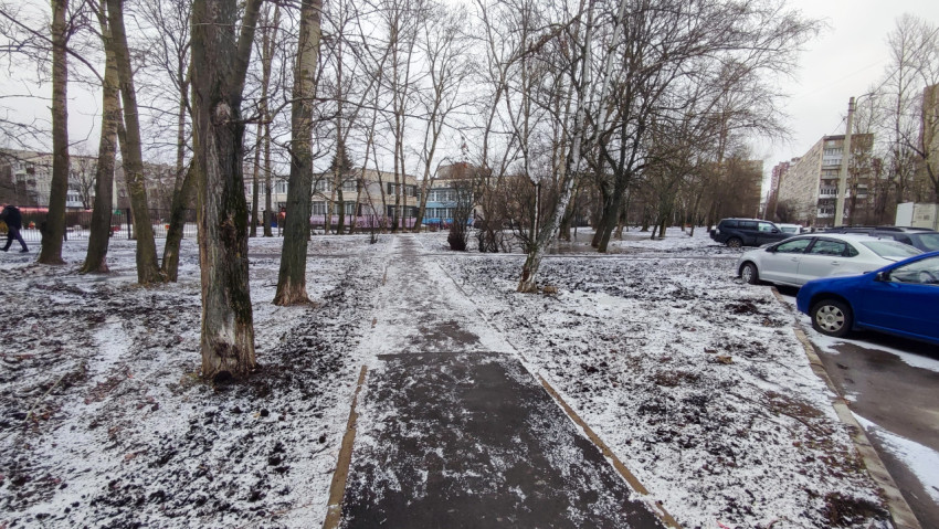 Асфальтовая тропинка через заснеженный городской двор