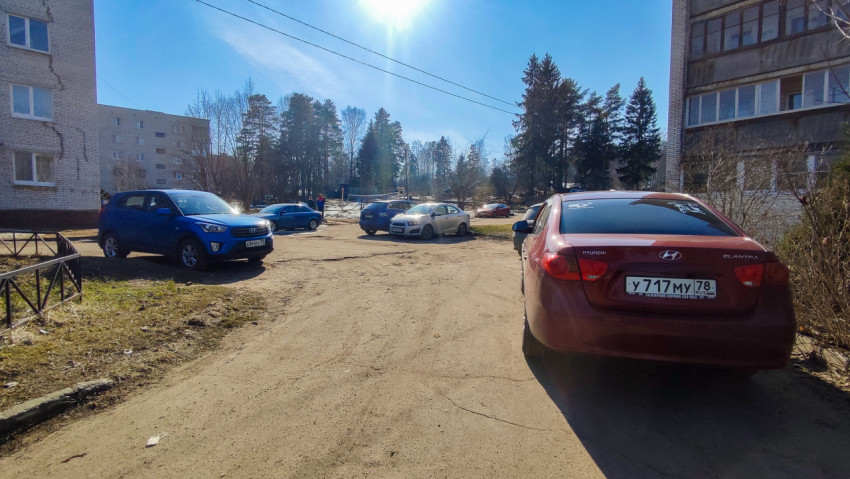 Дворовая парковка с машинами на фоне леса