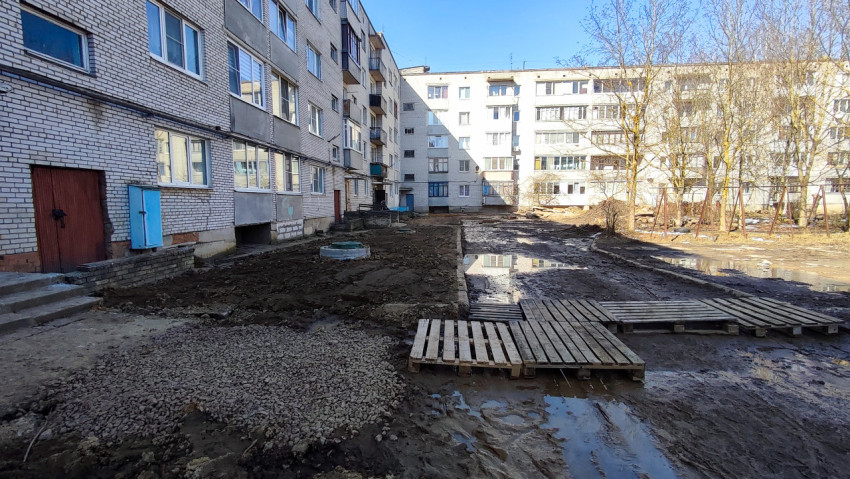 Фасад жилого дома с паллетами на грязной дворовой территории