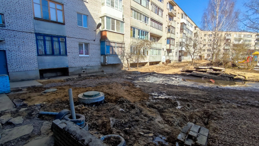 Грязная дворовая территория с остатками стройматериалов и лужами