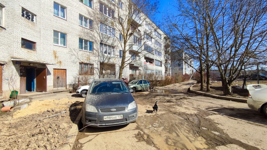 Двор жилого дома с припаркованными автомобилями и грязью на дороге