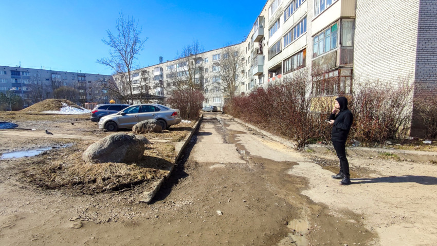 Молодой человек стоит у многоэтажки в жилом квартале весной