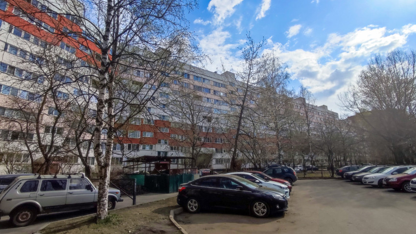 Многоэтажный жилой дом с припаркованными автомобилями во дворе